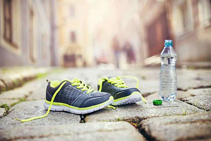 running shoes with a bottle of water on a brick road