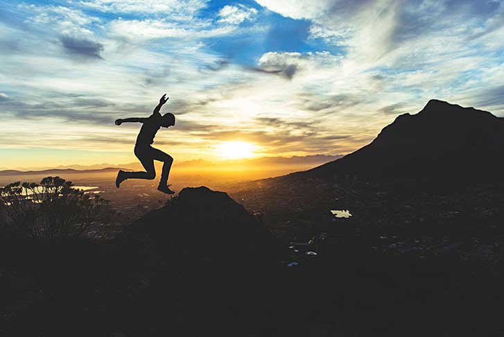 man jumping in the air with mountains in the background