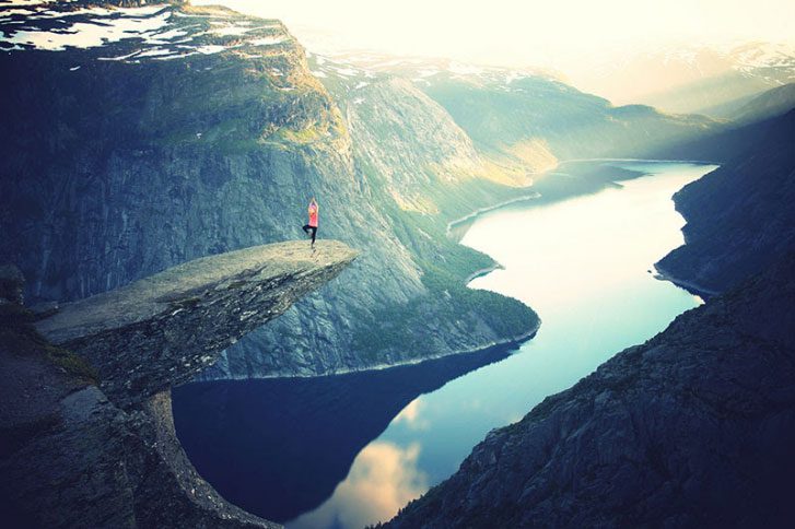 woman doing a yoga pose high up over water